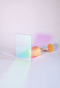 Close-up of multi colored glass on table against white background