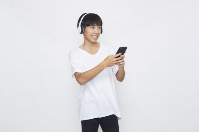 Young man using mobile phone against white background