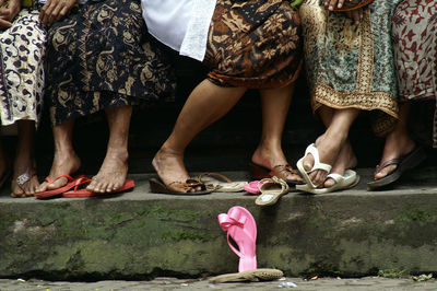 Low section of women standing by sandal