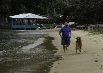 Rear view of woman with dog walking in water