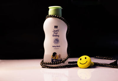 Close-up of toy bottle on table against black background