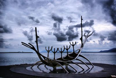 Bicycle moored on beach against sky