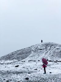 Rear view of woman on snow covered land against sky