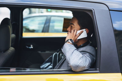 Businessman talking on smart phone while sitting in taxi