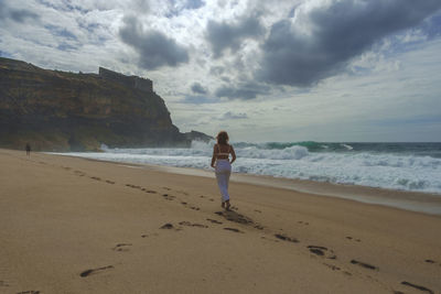 Full length of man standing on beach against sky