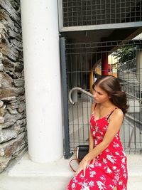 Woman looking away while standing against wall