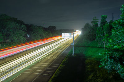 Light trails on road against sky at night