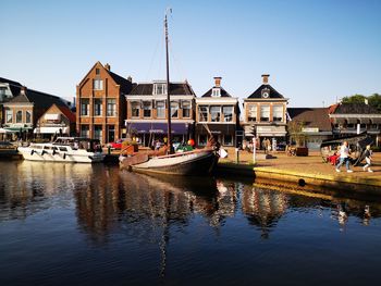 Boats moored in canal by buildings against sky