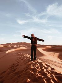 Woman standing on sand dune in sahara desert 