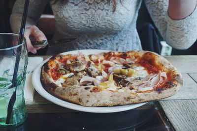 Midsection of woman eating pizza at restaurant