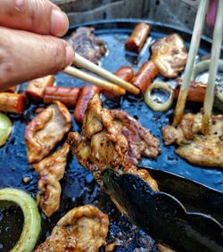 Close-up of person preparing food on barbecue grill