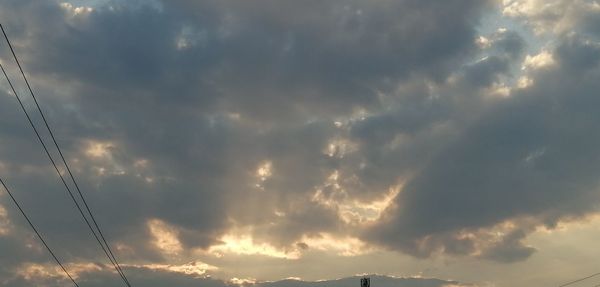 Low angle view of cables against dramatic sky