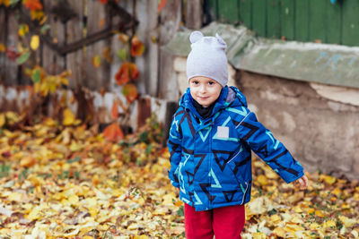 Happy child walking through autumn foliage. smiling boy playing with autumn leaves outdoors