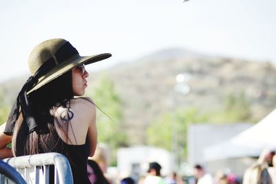 Portrait of woman wearing hat standing against cars