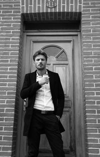 Portrait of young man standing in front of building