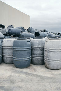 Rows of shabby metal barrels placed in shabby industrial place of factory on cloudy day