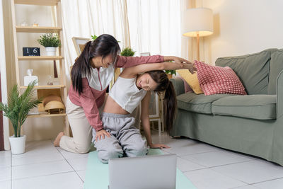 Side view of mother and daughter sitting at home