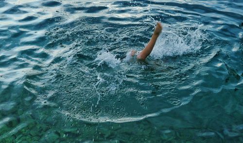 Low section of child swimming in sea