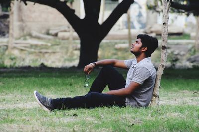 Side view of man sitting on field