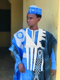 Young man in traditional clothing standing against wall