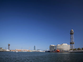 Sea by buildings against clear blue sky