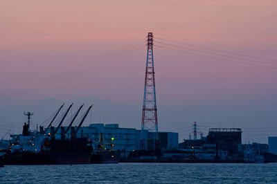 Cranes at commercial dock against sky during sunset