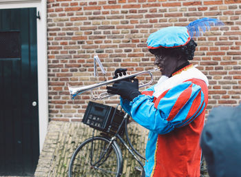 Man with bicycle leaning against brick wall