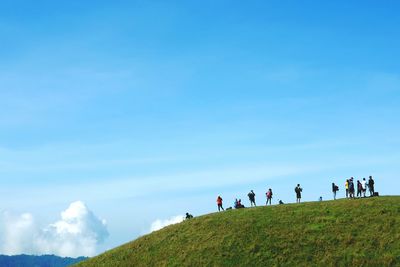 People on mountain against blue sky