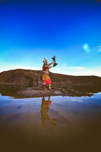 Reflection of person standing on water against blue sky