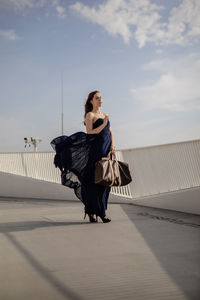 Young woman with bag standing on building terrace