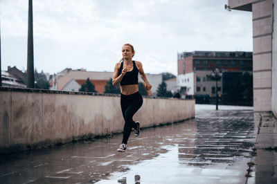 Full length of woman running on wet street