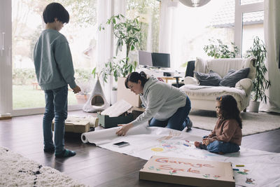 Mother with son and daughter drawing on textile in living room at home