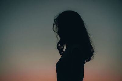 Portrait of silhouette woman against gradient sky background