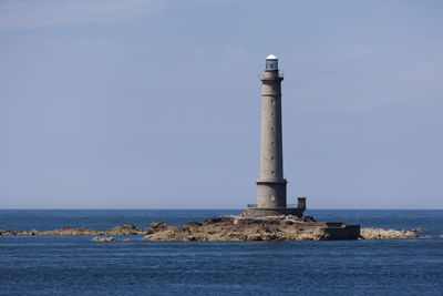 Lighthouse by sea against clear sky