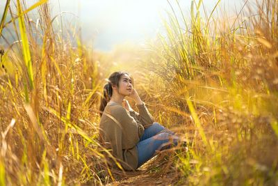 Side view of young woman sitting on field