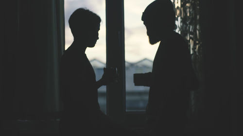 Silhouette couple standing by window