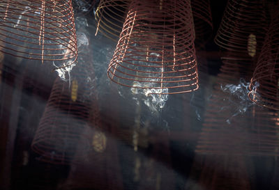 Low angle view of burning spiral incenses hanging at temple