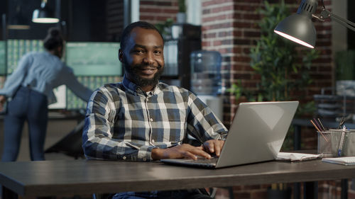 Portrait of smiling businessman using computer at office