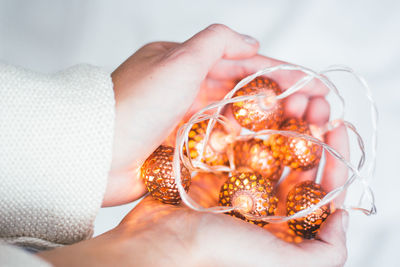 Close-up of hands holding illuminated string light