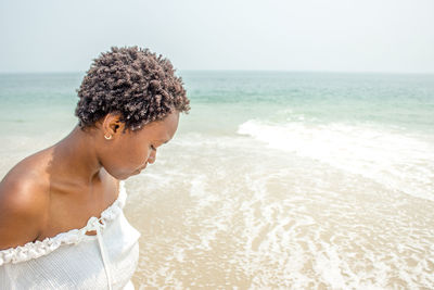 Young woman on beach against clear sky