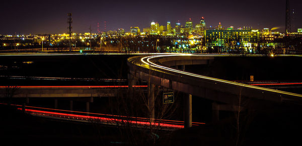 Light trails on elevated road against cityscape at night