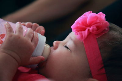 Close-up of baby girl with milk bottle sleeping at home