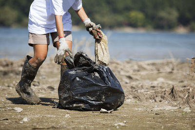 Low section of woman cleaning beach