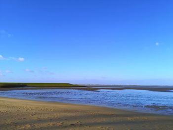 Scenic view of beach against blue sky