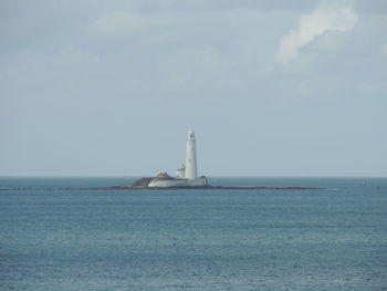 Lighthouse by sea against sky