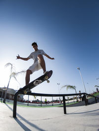 Man jumping on skateboard against clear sky