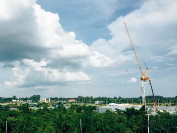 Crane by building against sky in city