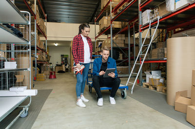 Female coworker looking at manager using digital tablet in warehouse