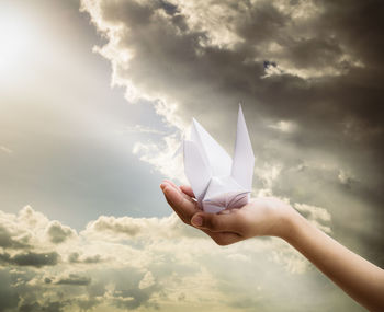 Midsection of person holding paper against sky