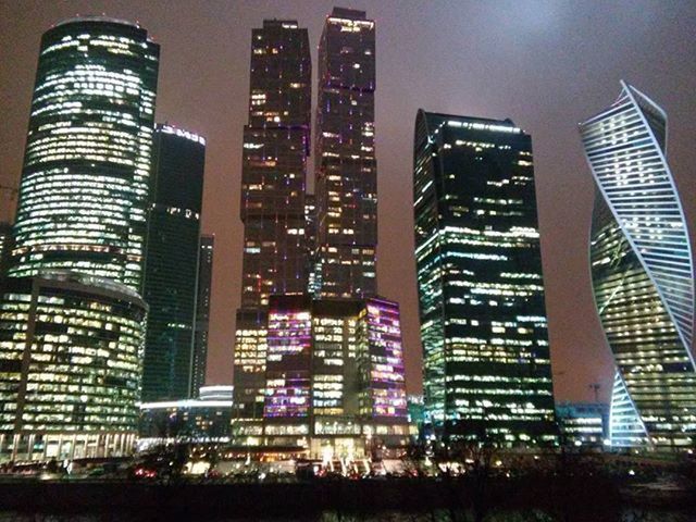 LOW ANGLE VIEW OF MODERN BUILDINGS AGAINST SKY AT NIGHT